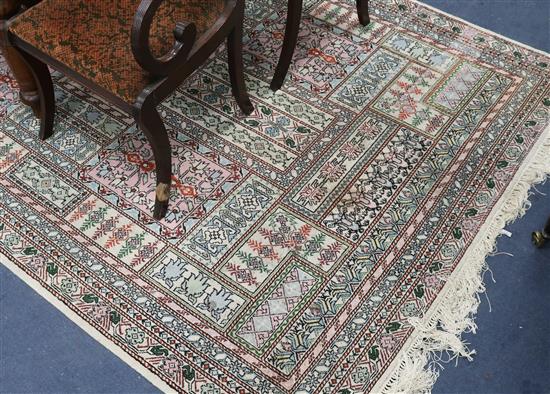 A Persian cream ground rug, woven with panels of stylised flowers 245cm x 173cm